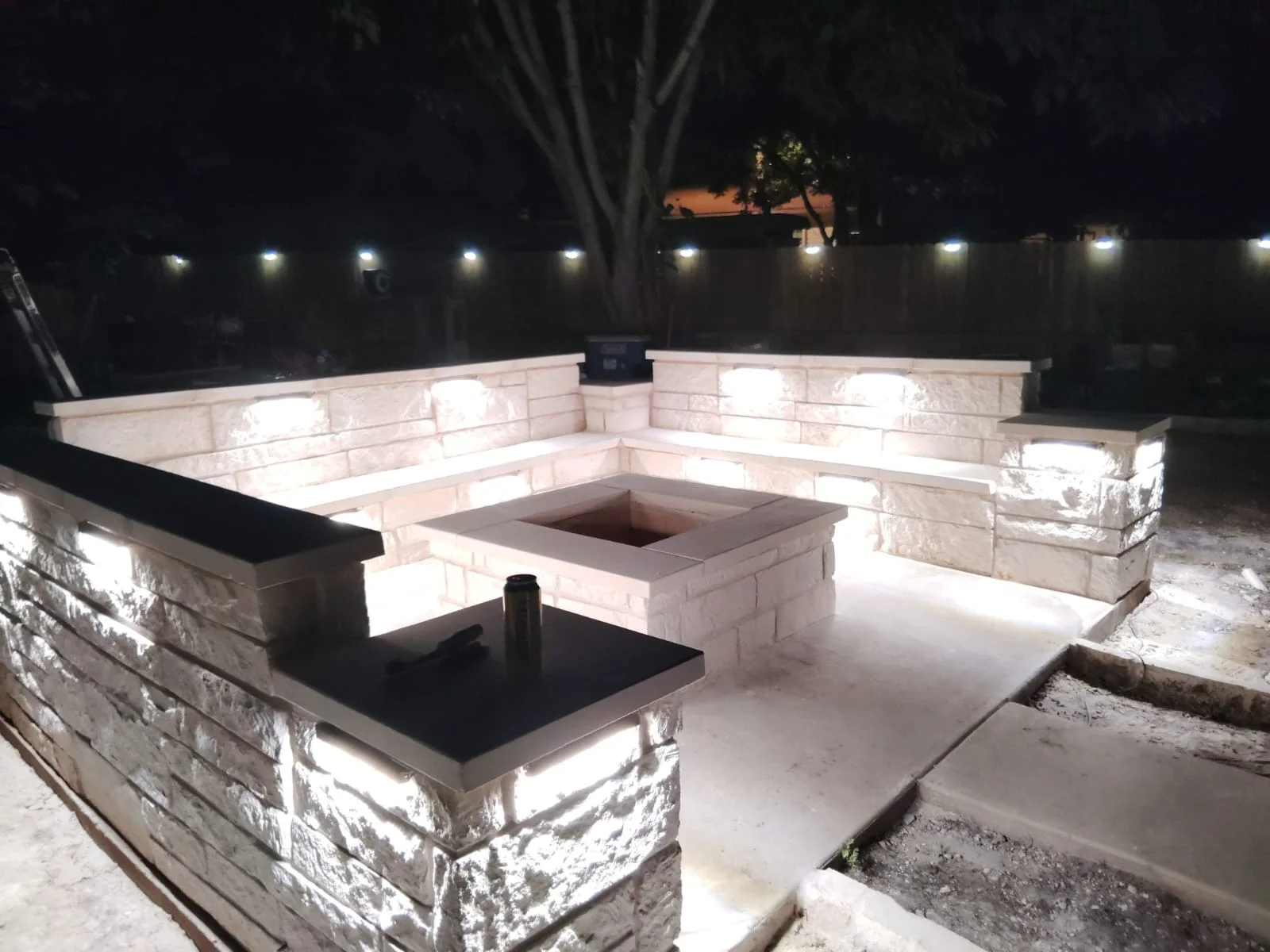 Custom stone fire pit and illuminated seating wall in Greater San Antonio